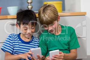 Happy siblings using mobile phone in living room