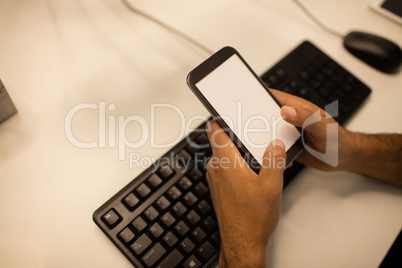 Cropped image of businessman holding mobile phone while sitting at desk