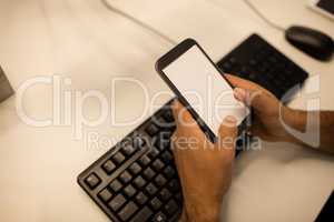 Cropped image of businessman holding mobile phone while sitting at desk