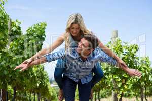 Happy young couple piggybacking at vineyard