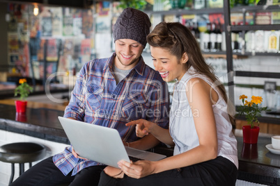 Cheerful friends using laptop in restaurant