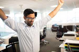 Happy businessman with arms raised at office