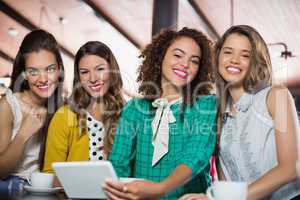 Female friends using digital tablet in cafe