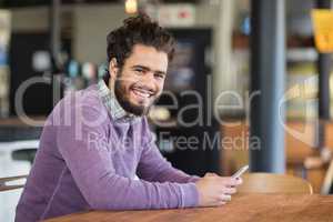 Portrait of man using mobile phones while sitting in restaurant