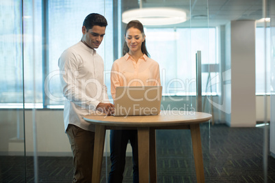 Colleagues using laptop in modern office