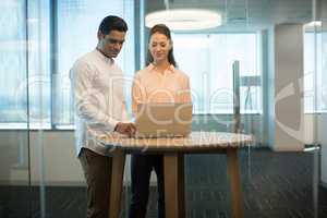 Colleagues using laptop in modern office