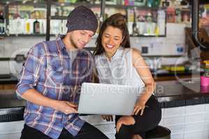 Happy friends using laptop in restaurant