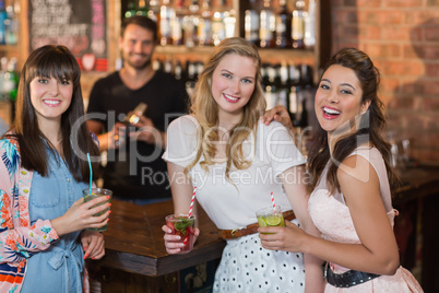 Portrait of cheerful female friends holding drinks in bar