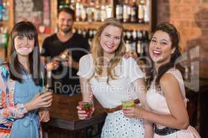 Portrait of cheerful female friends holding drinks in bar