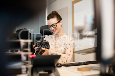 Smiling female photographer using camera at creative office