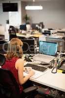 Businesswoman holding coffee cup while working in office