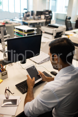 Businessman using digital tablet while sitting at his desk in office