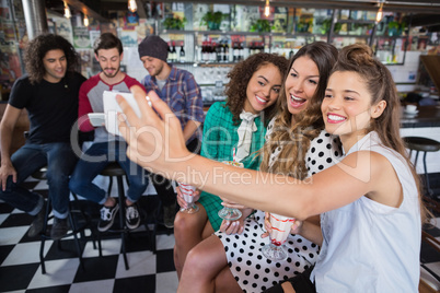 Cheerful female friends taking selfie in restaurant
