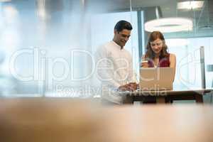 Business people having coffee while using laptop in office