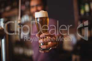Male bar tender giving glass of beer