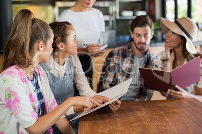 Friends discussing while giving order to waitress