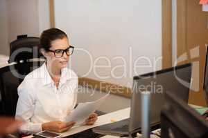 Businesswoman holding documets while looking at laptop