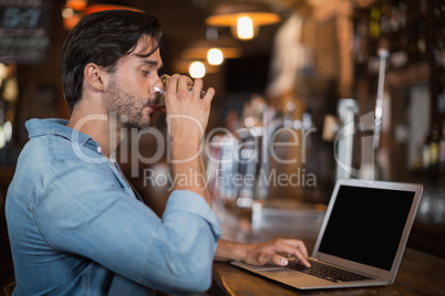 Man drinking beer while using laptop in restarant