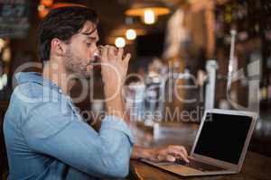 Man drinking beer while using laptop in restarant