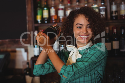 Portrait of female bartender mixing a cocktail drink in cocktail shaker