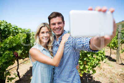 Happy couple taking selfie through mobile phone at vineyard