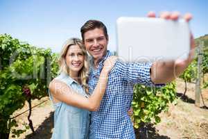 Happy couple taking selfie through mobile phone at vineyard