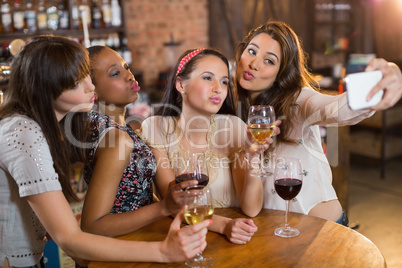 Female friends taking selfie while holding wineglasses