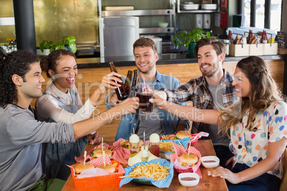 Cheerful friends toasting beer bottles in pub