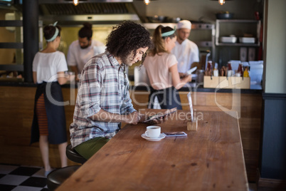 Young man using digital tablet in restaurant