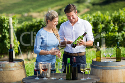 Happy man showing wine bottle to woman while standing by table