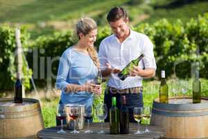 Happy man showing wine bottle to woman while standing by table