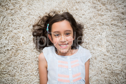 Portrait of smiling girl lying on rug in living room