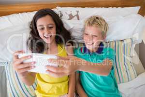 Siblings taking selfie on mobile phone in bedroom