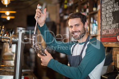 Portrait of bartender pouring beer from tap