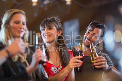 Smiling friends holding beer bottles