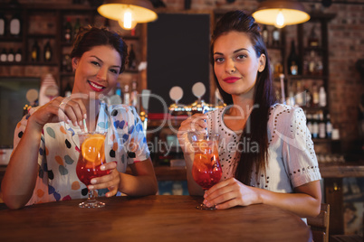 Portrait of two young women having cocktail drinks