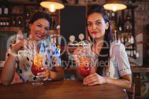 Portrait of two young women having cocktail drinks
