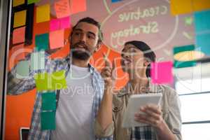Male and female executives discussing over sticky notes