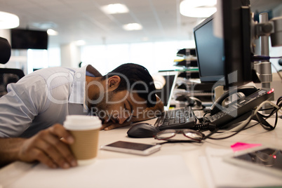 Tired businessman sleeping by desktop computers at office