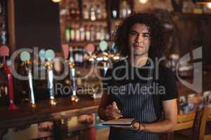 Portrait of young waiter writing on diary