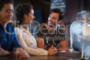 Smiling friends interacting at bar counter