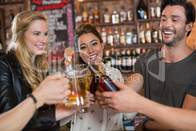 Cheerful friends toasting beer mugs and bottles