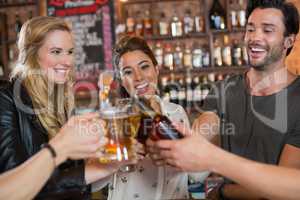 Cheerful friends toasting beer mugs and bottles