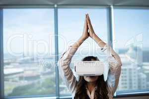 Businesswoman practicing yoga while using virtual reality glasses