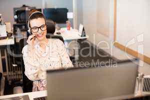 Smiling businesswoman using headset at office