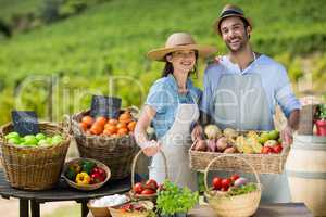 Smiling couple standing by fresh fruits and vegetables