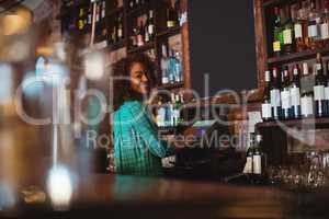 Portrait of beautiful female bar tender using electronic machine