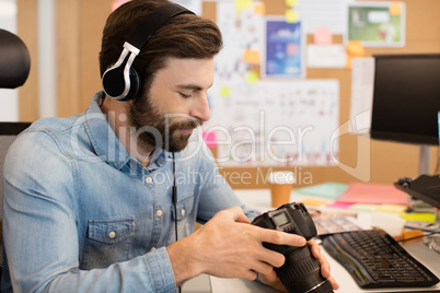 Photographer wearing headphones while using camera in creative office
