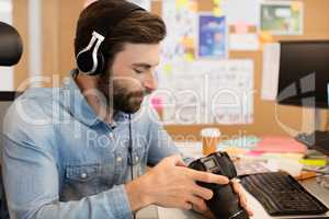 Photographer wearing headphones while using camera in creative office