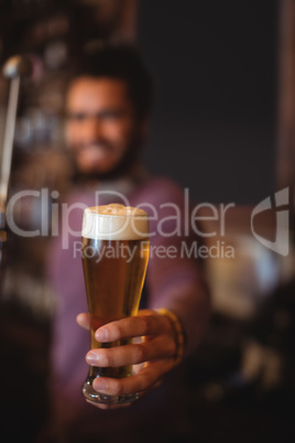 Male bar tender holding glass of beer